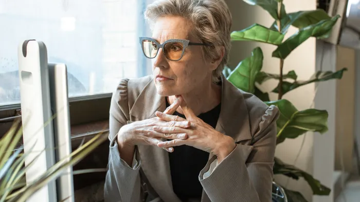 Empresaria pensativa en su escritorio evaluando una decisión