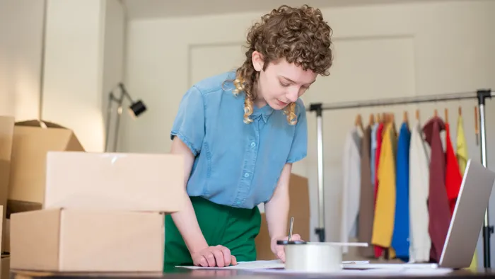 Emprendedora preparando pedidos de su tienda online junto a su laptop