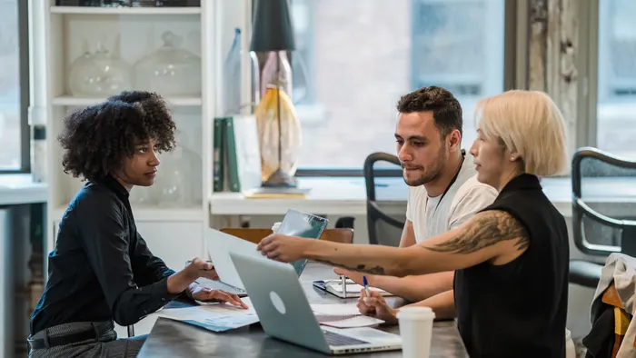 Tres colegas revisan juntos el trabajo en una laptop