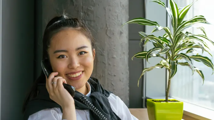 Mujer atendiendo con una sonrisa una llamada de un cliente en su oficina