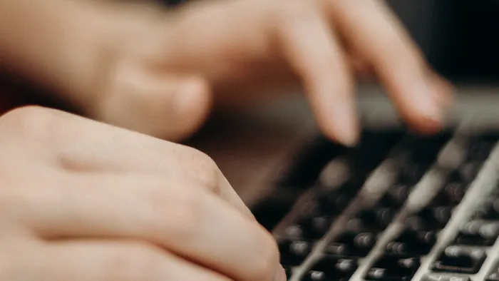Primer plano de unas manos escribiendo en el teclado de una laptop