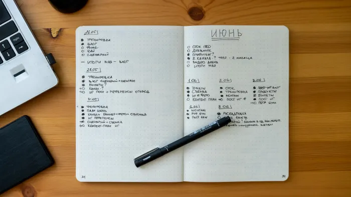 Cuaderno abierto con listas de tareas escritas a mano sobre un escritorio de madera, junto a una laptop