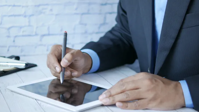 Hombre con traje firmando sobre la pantalla de una tablet con un lápiz digital