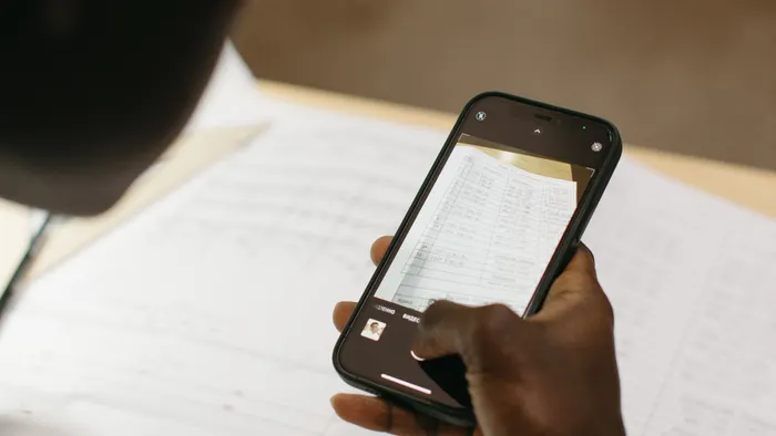 Persona fotografiando con su teléfono un documento con una tabla impresa