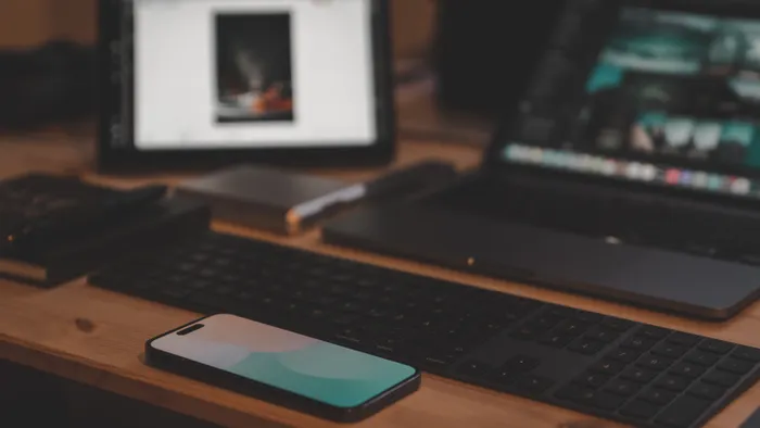 Escritorio de madera con una tablet, una laptop, un teclado y un teléfono móvil bajo luz cálida